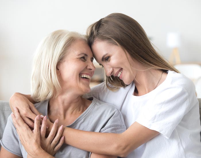 Two woman hugging and smiling at each other